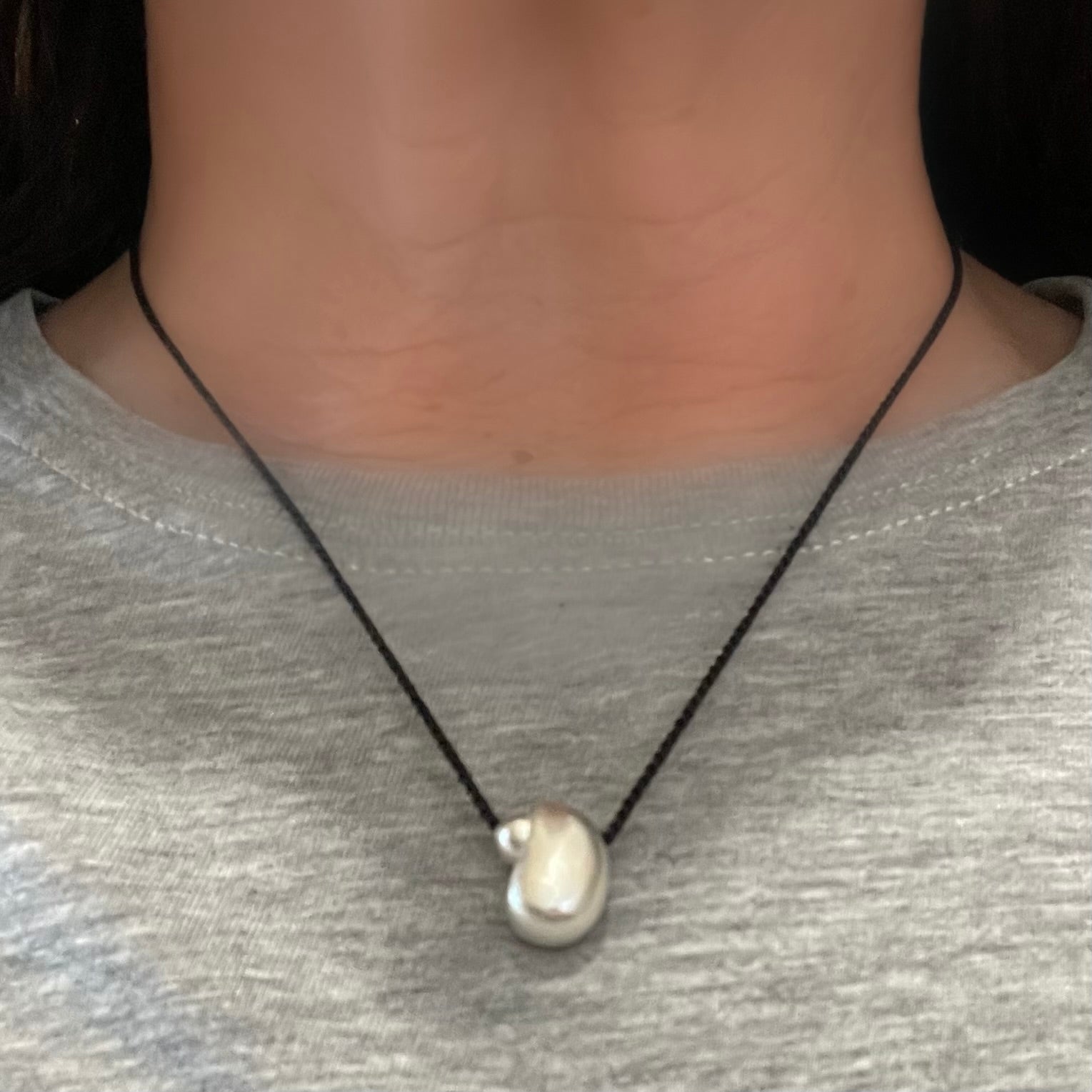 small silver abstract pendant representing mother and child